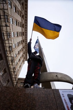 Ukraynalı vatansever bir anıtın üzerinde ulusal bayrak sallıyor. Kyiv - 23 Mart 2024