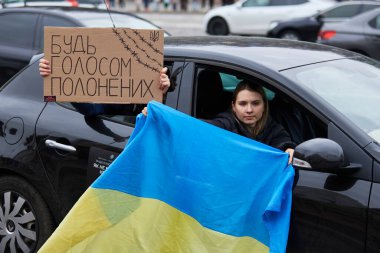 Vatansever Ukraynalı kadın, Kyiv 'de 24 Mart 2024' te yapılan bir halk gösterisinde hareket halindeki bir arabanın camında bayrak ve 
