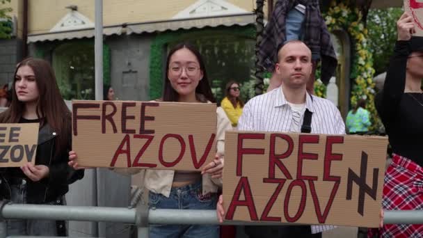 アジア人女性とウクライナ人男性は マリポルとアゾフスタルの守備兵を捕らえるためにウクライナで平和的な集会で フリーアゾフ の旗でデモを行った キエフ 2024 — ストック動画