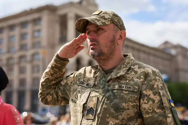Ukrainische Soldaten Salutieren Während Der Nationalhymne Bei Einer Öffentlichen Veranstaltung lizenzfreie Stockbilder