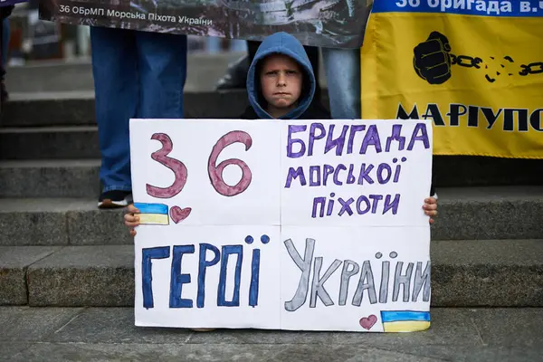 悲しいウクライナ人の少年が 第36海兵旅団 という旗を掲げた ウクライナの英雄たち の公開デモ キエフ 2024 ストック写真
