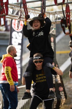 Neşeli genç kız, Sparta Yarışı 'nda arkadaşının sırtında otururken çok platformlu golf sahasını bitiriyor. Kyiv - 20 Nisan 2024