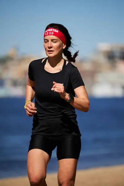 キエフでのスパルタレース競技の間に砂浜で走っているウクライナの女性 4月20日 2024 ストックフォト