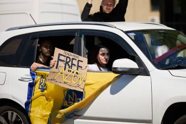 Ukraynalı aktivistler Azov tugayının bayrağını taşıyan bir arabaya binip 28 Nisan 2024 'te Kyiv' de düzenlenen bir halk gösterisinde 
