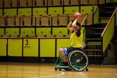 Tekerlekli sandalyedeki basketbolcu adaptasyon maçında topu fırlatıyor. Kyiv - 12 Aralık 2023