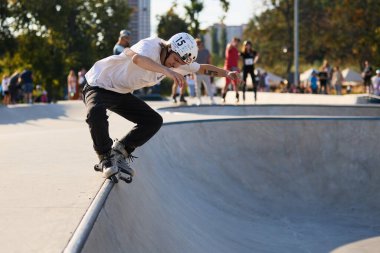 Roller skating in skate pool. In-line skater doing mistrial grind on coping rail. Kyiv - 4 August,2024 clipart