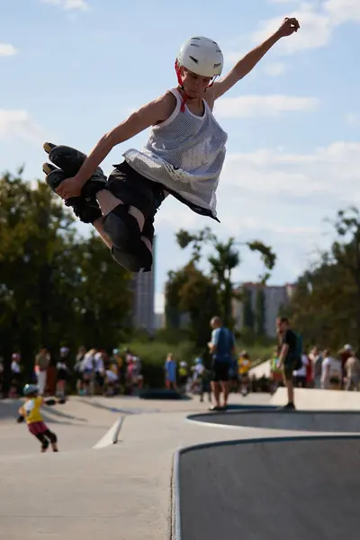 stock image Roller blader jumping high out of a skate pool in skatepark. Young in-line skater performing mute grab trick. Kyiv - 4 August,2024