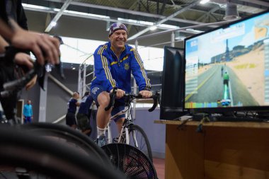 Neşeli Ukraynalı gazi bisiklet eğitmeni standında bisiklet sürüyor. Kyiv - 13 Aralık 2023