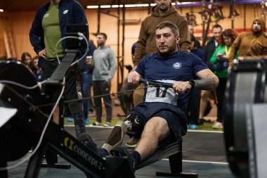 Ampütasyonu olan bir sporcu spor salonunda Concept2 ergometre makinesinde kürek çekiyor. Kyiv - 13 Aralık 2023