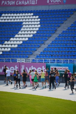 Group of running people at stadium during charitable training event. Kyiv - 10 August,2024 clipart