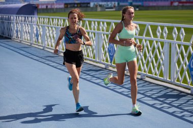 Yazın stadyumda maraton koşan iki sağlıklı kadın. Açık havada egzersiz yapan Ukraynalı dişiler. Kyiv - 10 Ağustos 2024
