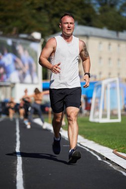 Atletik bir adam sabah bir pistte koşuyor. Kyiv - 7 Eylül 2024