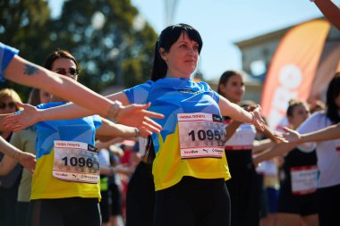 Kyiv 'de Nova Poshta' nın 22 Eylül 2024 'te düzenlediği uyarlamalı maraton koşusu öncesinde gerinen vatansever Ukraynalı kadın.