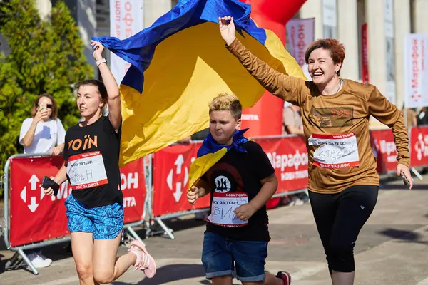 Neşeli Ukraynalı aile, elinde ulusal bayrak ile bir yardım maratonu düzenliyor. Yaralı askerler için para toplamaya koşan mutlu Ukraynalılar. Kyiv - 22 Eylül 2024