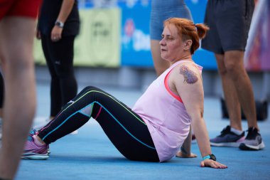 Yetişkin bir kadın Ukrayna 'daki fonksiyonel eğitim etkinliği sırasında setlerin arasında dinleniyor. Kyiv - 15 Eylül 2024