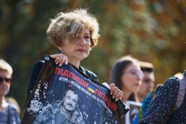 Üzgün Ukraynalı kadın, Ukrayna Silahlı Kuvvetleri askerleri adına dilekçe imzalamak için elinde bir pankartıyla yürüyor. Kyiv - 28 Eylül 2024