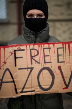 Kar maskeli genç Ukraynalı kız Azov 'un posteriyle poz veriyor. Kyiv - 24 Kasım 2024