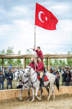 Etnospor Kultur Festivali 'nde üç Türk at binicisi geleneksel kırmızı ve beyaz bayrak taşıyor. İstanbul - 11 Mayıs 2018