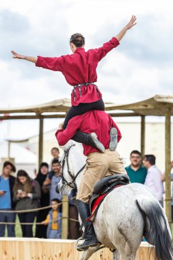 Etnospor Kultur Festivali 'nde dört nala koşan bir ata iki kişi numara yapıyor. İstanbul - 11 Mayıs 2018