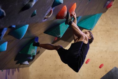 Tırmanışçılar dik bir duvara tutunmuş kayalık bir spor salonunda tutunuyorlar. Kyiv - 23 Aralık 2023