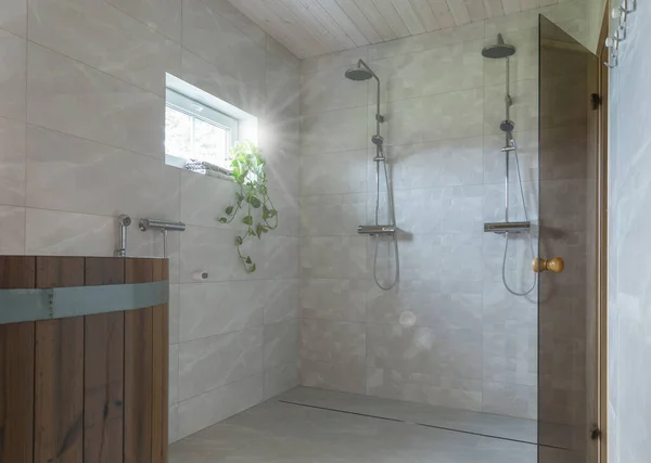 Finnish bathroom with wooden sauna, open showers and marble walls and floors. Modern spa salon interior with glass door in house. Scandinavian style