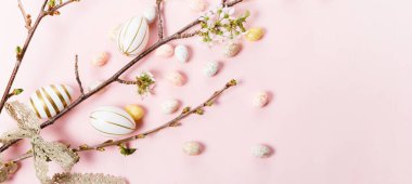 Kiraz çiçekli renkli Paskalya yumurtaları pembe arka planda yatıyordu. Mutlu Paskalyalar