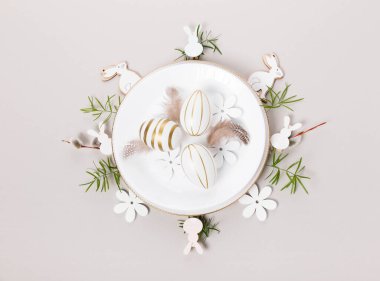 Paskalya konsepti. Süslü beyaz tabak, Paskalya yumurtaları ve bahar çiçekleriyle süslenmiş. Havalı paskalya düzlüğü mavi uzanıyordu