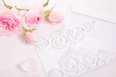 Mektup, zarf ve pembe güller. Düğün davetiyesi ya da aşk mektubu. Sevgililer Günleri, anneler günü konsepti, üst görünüm, düz görünüm, genel görünüm