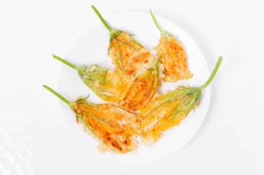 Kızarmış kabak çiçekleri hamurda, kabak çiçekleri beyaz arkaplanda.