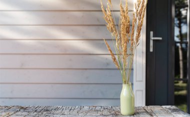 Poster kartı, ahşap masadaki sonbahar otları ahşap modern evin duvarına karşı. Sonbahar arkaplanı