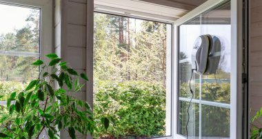 Ev penceresinde çalışan gelişmiş cam temizleme robotu. Bahar temizliği ve ev temizliği, temizlik hizmetleri veya DIY, bahar havası. Modern evler, zahmetsiz bakım, güvenlik ve zaman tasarrufu için.