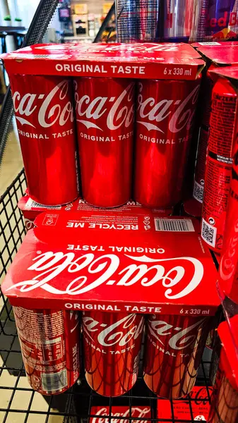 Panevezys, Litvanya - 5 Nisan 2025. Çoklu paket Coca-Cola Orijinal Tat ve süpermarketin içindeki metal alışveriş arabasında kırmızı damga. Küresel soda, meşrubat, perakende ürün