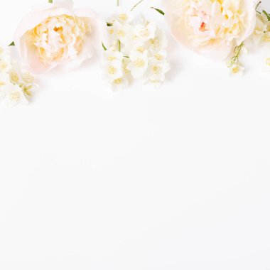 Yumuşak pastel şakayıklar ve beyaz yasemin çiçekleri ile kare çiçek düzeni temiz beyaz arka planda hafif üst sınır oluşturur. Kozmetik markalaşma, bahar tebrik kartları, minimalist ürün tasarımları