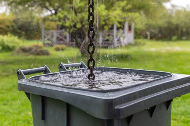 Yağmur suyu zinciri arka bahçedeki plastik fıçıya sıçrar, sürdürülebilir yaşam tarzı, iklim adaptasyonu, kırsal bölge dışı yaşam, yeşil çevre konsepti için eko su toplama çözeltisi