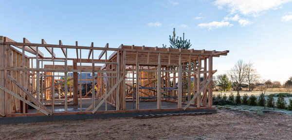 Строительство каркаса деревянного дома на строительной площадке, концепция устойчивой архитектуры, экологически чистый жилой проект, столярная конструкция, строительство наружного жилья под ясным голубым небом
