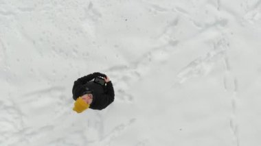 Aerial top-down view of a man launching drone in a snow covered pine forest. Flying over and shooting rime ice and hoar frost covering trees. Modern technologies in scenic winter landscape.