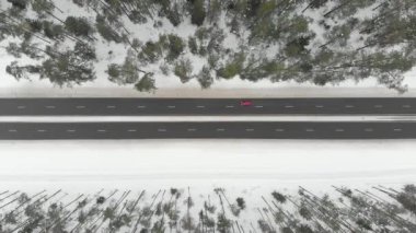 Ağaçlar arasında iki şeritli bir yol olan karla kaplı ormanın yukarıdan görünüşü. Rime buzu ve ağaçları kaplayan buz kütleleri. Manzaralı kış manzarası.