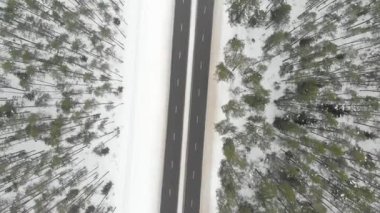 Ağaçlar arasında iki şeritli bir yol ile karla kaplı ormanın yukarıdan aşağıya dönen manzarası. Rime buzu ve ağaçları kaplayan buz kütleleri. Manzaralı kış manzarası.