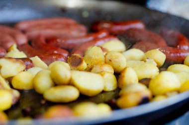 Litvanya 'nın Vilnius kentindeki bahar pazarında geleneksel kızarmış patates ve sosis pişiriliyor. Paskalya Festivali 'nde çeşitli sokak yemekleri.