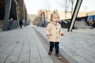 Komik çocuk güneşli bahar gününde dışarıda eğleniyor. Şehirdeki çocuk. Şehir parkında oynayan bir çocuk. Çocuklu aileler için aktif eğlence.