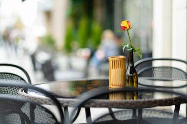 Litvanya 'nın Vilnius şehrinde güzel bir yaz gününde, gül çiçeğiyle süslenmiş açık hava restoran masası. Dışarıda yemek yemek..