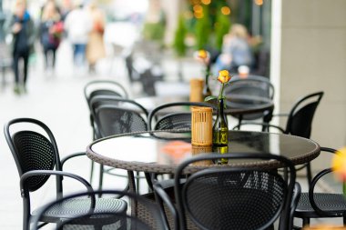 Litvanya 'nın Vilnius şehrinde güzel bir yaz gününde, gül çiçeğiyle süslenmiş açık hava restoran masası. Dışarıda yemek yemek..