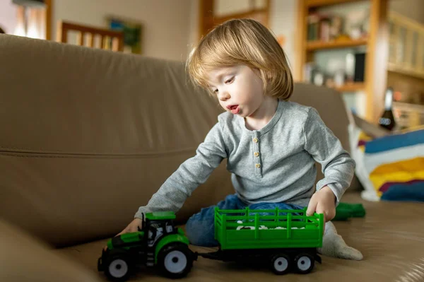 緑のおもちゃのトラクターで家で遊んでかわいい幼児の男の子 おもちゃで楽しんでいる小さな子供 屋内で過ごす子供 — ストック写真