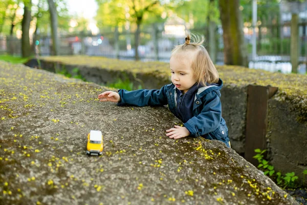 黄色のおもちゃの車で屋外で遊んでかわいい幼児の男の子 おもちゃで遊ぶ小さな子供 — ストック写真