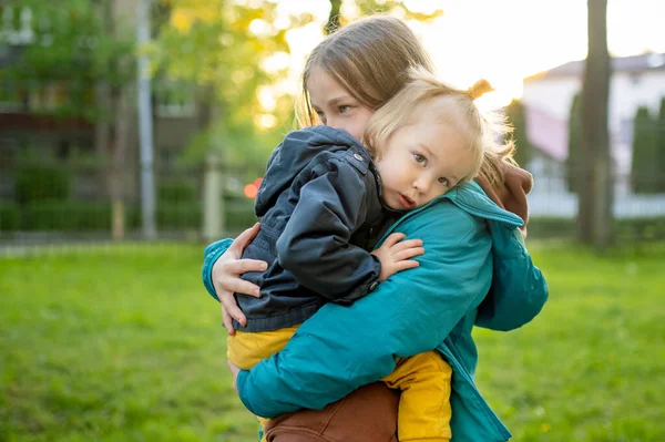 可爱的姐姐抱着她蹒跚学步的弟弟 可爱的少女拥抱着她的小弟弟 孩子们探索自然 兄弟们相处得很好 — 图库照片