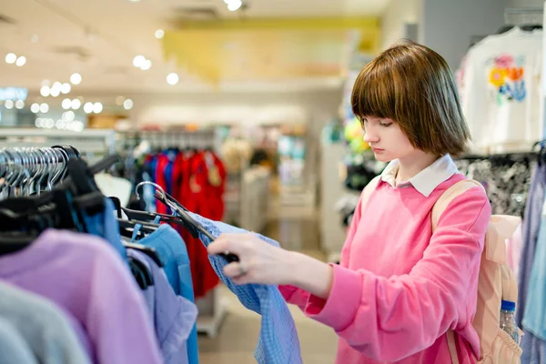 stock image Pretty teenage girl choosing new clothes in a shopping center. Teenager picking new clothing in a store. Sale, shopping and fashion concept.