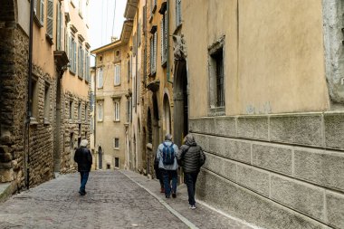 BERGAMO, İtalya - Nisan 2022: Milano 'nun kuzeydoğusundaki Bergamo şehrinin dar ortaçağ caddesi. Şehrin üst bölgesi olan Citta Alta 'nın manzarası Venedik duvarlarıyla çevrili. Bergamo, Lombardy, İtalya.