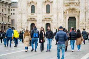 MILAN, ITALY - 2022: Bir grup insan eğleniyor, resim çekiyor ve Katedral Meydanı veya İtalya 'nın merkezindeki Piazza del Duomo' daki güvercinleri besliyor..