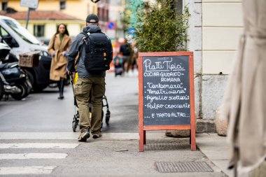 MILAN, İtalya - 2022: Milano 'nun merkezindeki işlek caddede, İtalya' nın kuzey Lombardiya bölgesinde bir metropol olan açık hava restoran menüsü. Milan, Lombardiya, İtalya.