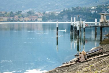 LECCO, İtalya - Nisan 2022: Turistler ve yerliler, Como Gölü kıyısındaki bir kasaba olan Lecco 'da güneşli bir bahar günü geçiriyorlar. Tipik İtalyan atmosferiyle büyüleyici bir yer. Lecco, Lombardy, İtalya.